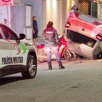 Mulher se distrai com celular, bate em carro estacionado e capota